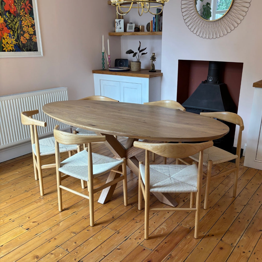 Wooden dining table with chairs in a room with wooden flooring and a fireplace.