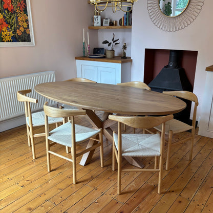 Wooden dining table with chairs in a room with wooden flooring and a fireplace.
