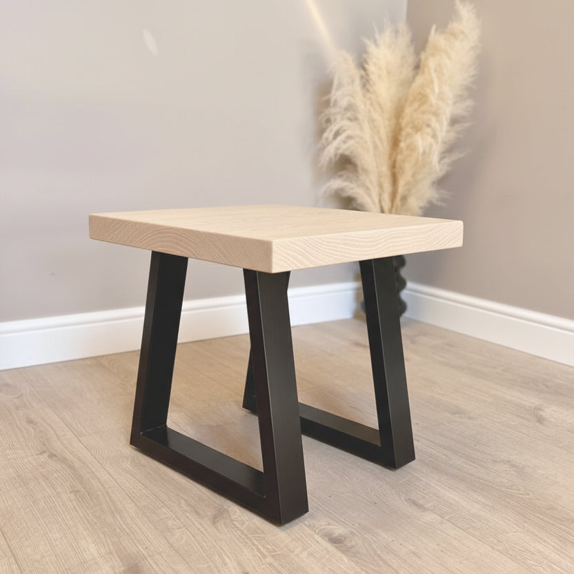 Ash Wooden side table with black metal legs on a wooden floor.