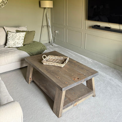 Wooden coffee table in a living room with a lamp and TV in the background.